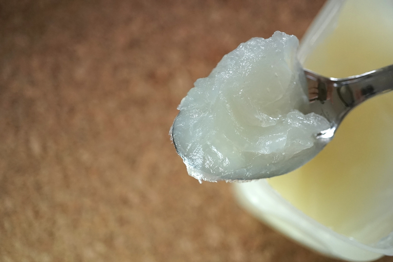 Person scooping Vaseline out of the container with a spoon.