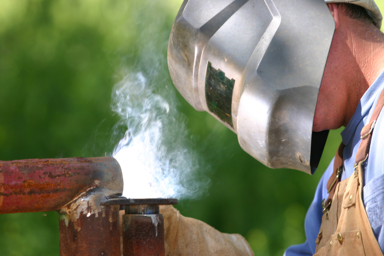 Welder wearing a welding helmet while laying a bead