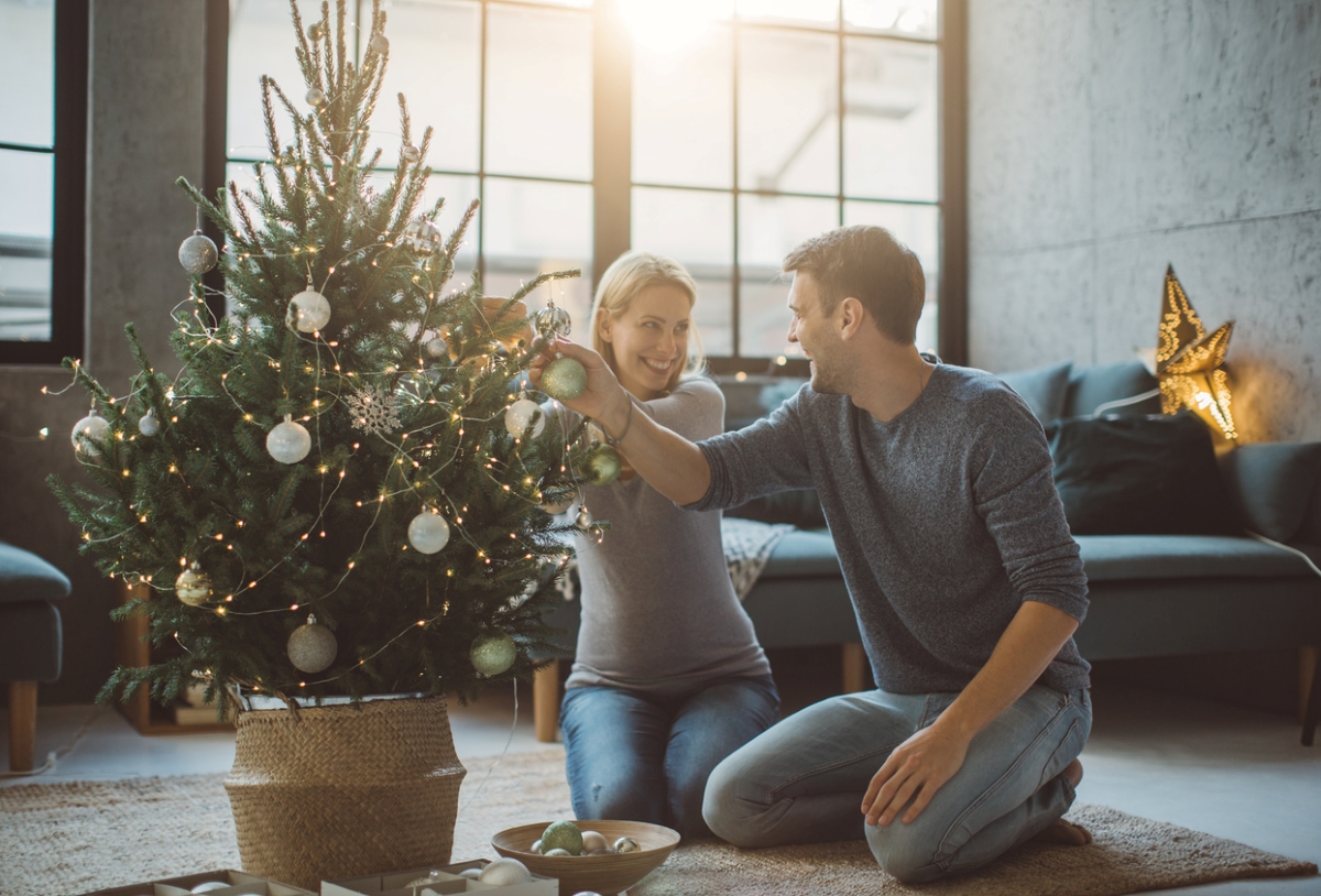 Couple decorating potted living Christmas tree.