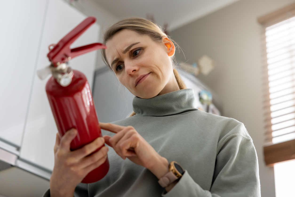 Puzzled woman reading the text on the side of a fire extinguisher.