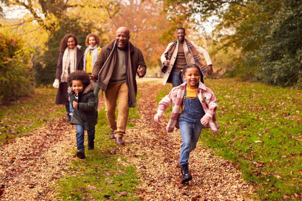 A family with young children walking on a path, surrounded by autumn leaves.