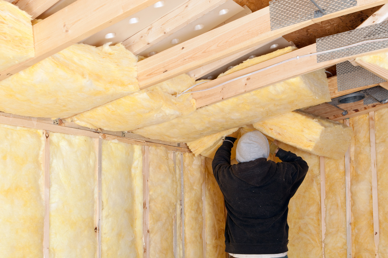 Man installing batt insulation in an attic.