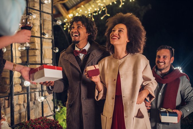 happy young people at front door holding presents