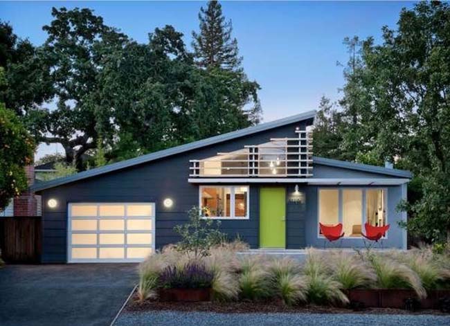 A midcentury modern home painted in dark gray paint with a lime green front door.