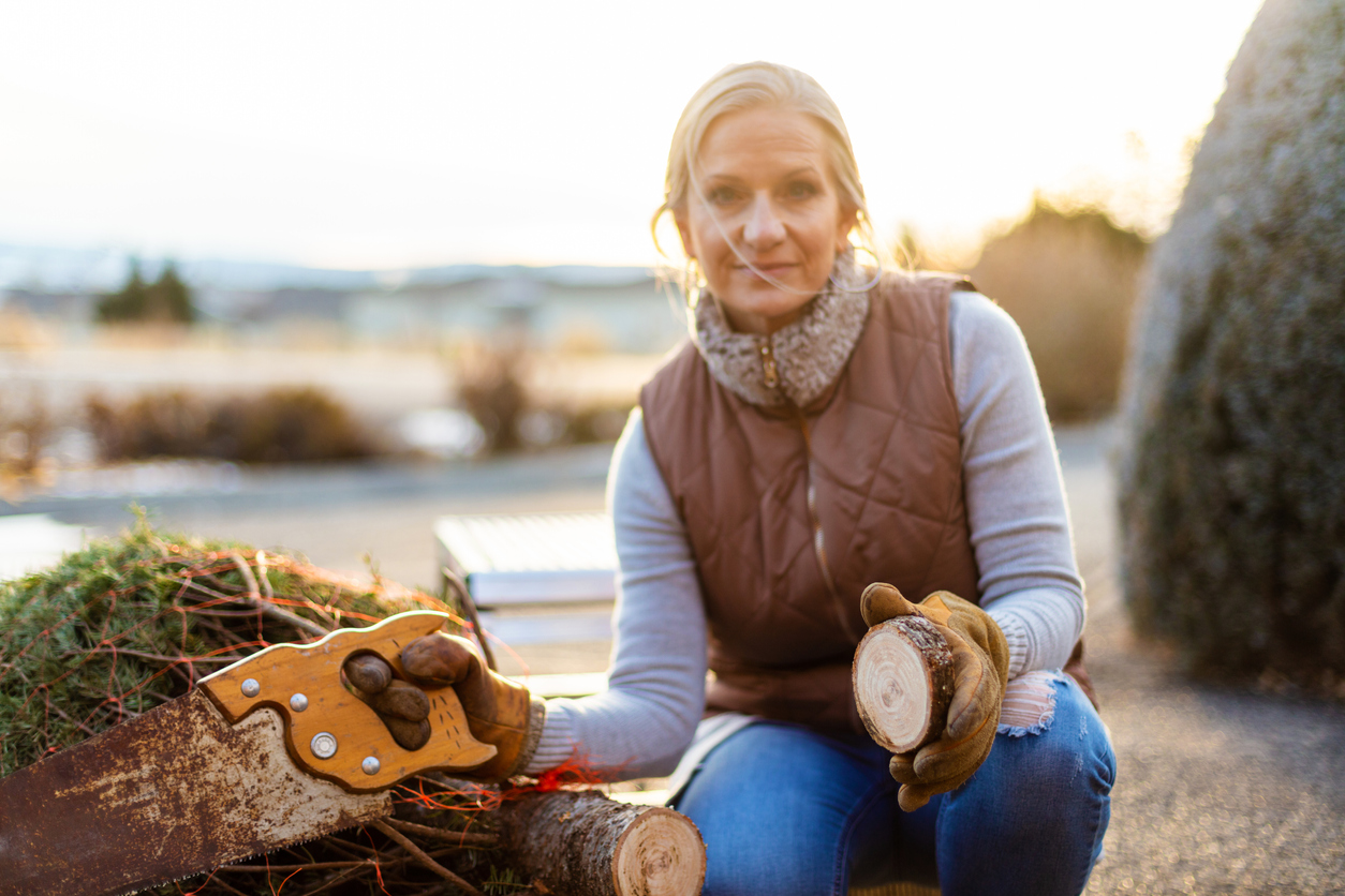 iStock-1293259985 Christmas tree care woman cutting tree trunk