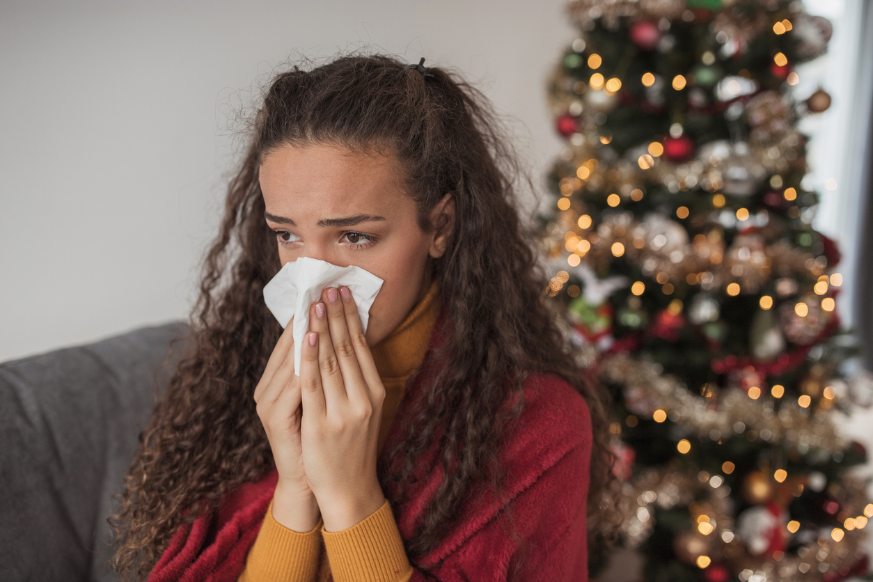 iStock-1440005583 christmas tree care woman sneezing in front of christmas tree