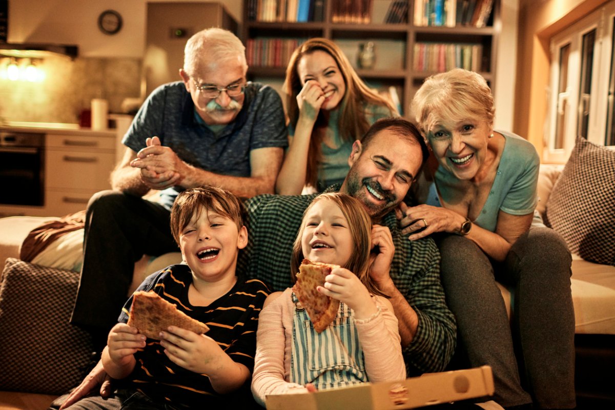 family with grandparents watching movies eating pizza