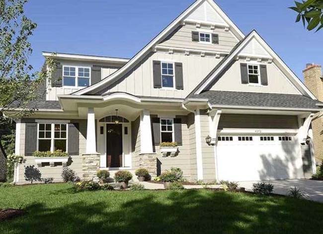 Putty and grey-colored house with a white garage door in a suburban neighborhood.