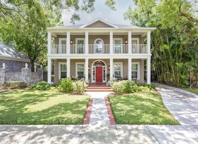 Taupe Georgian-style house with five pillars out front and a red front door.