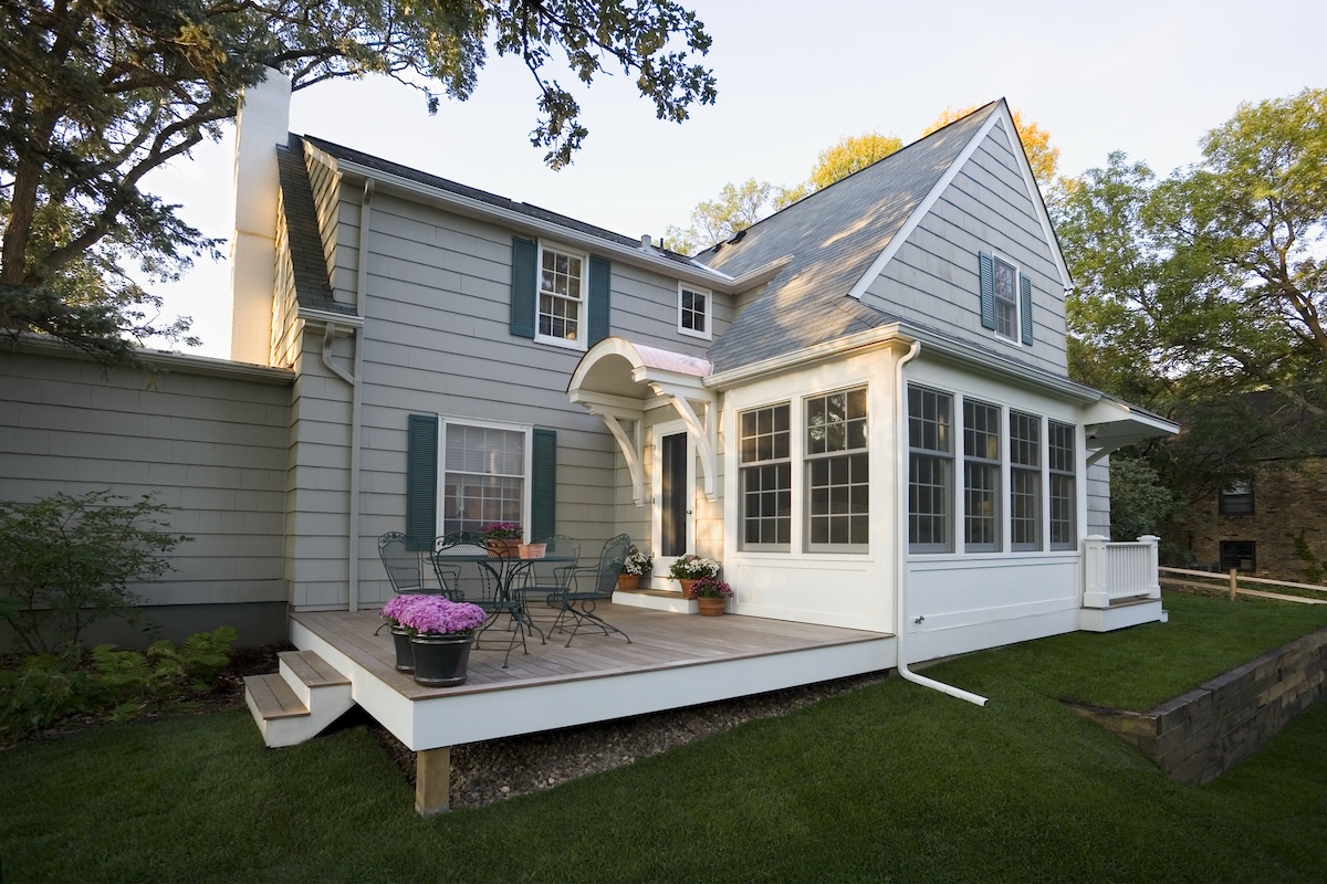 A gray home with a screen porch and teal-colored window shutters.