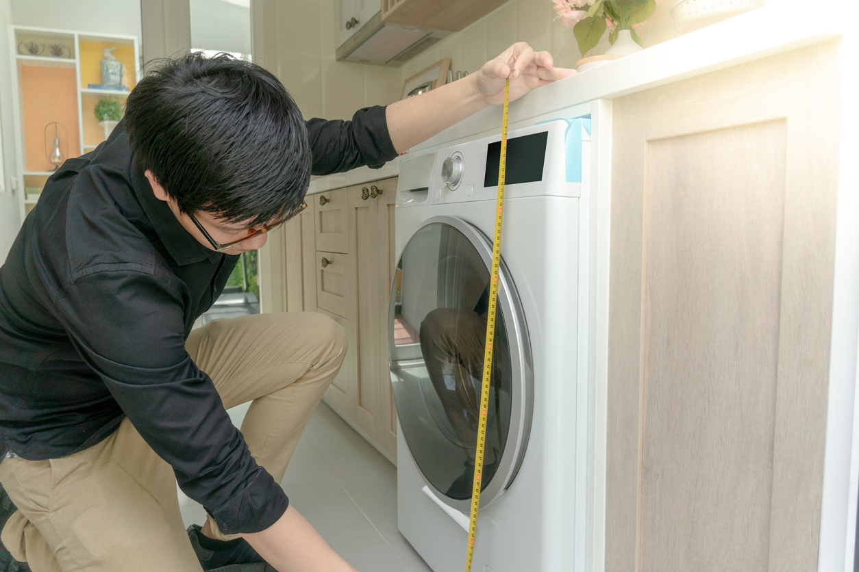 iStock-1035884128 Home Depot shopping man measuring height of washing machine