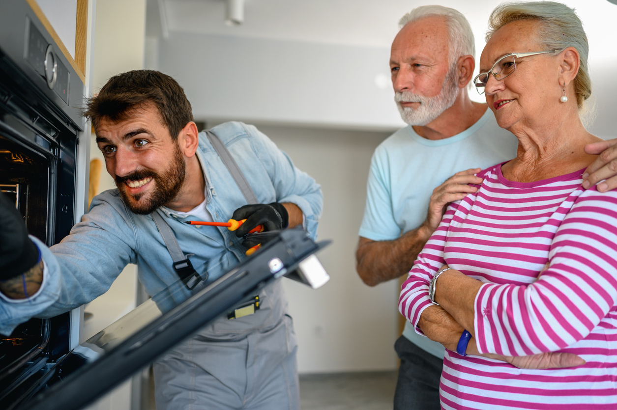 iStock-1278850705 productivity hacks repairman fixing senior couple's oven