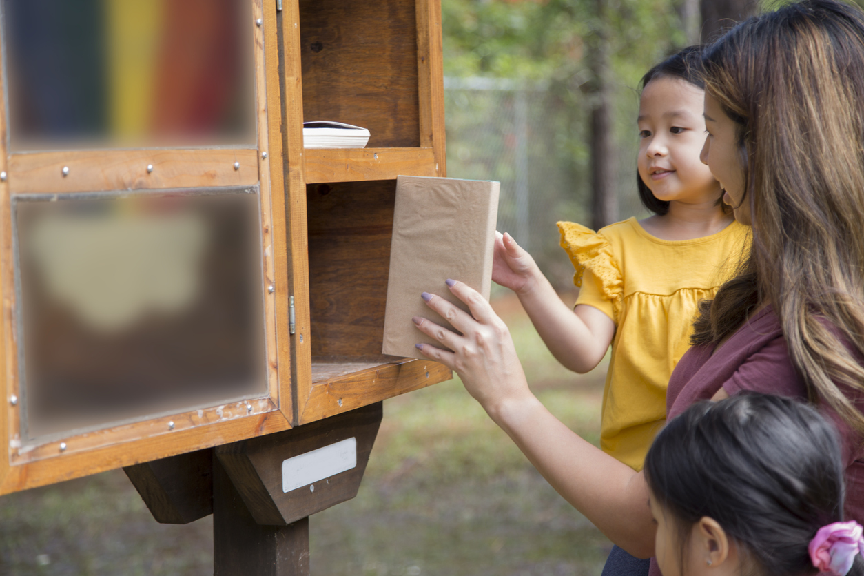 iStock-1352947054 volunteer opportunities family exchanging books at community library outdoors