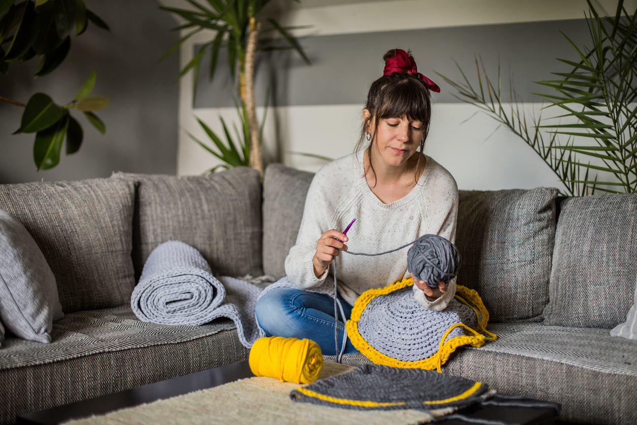 iStock-1419287021 how to crochet for beginners woman crocheting on her bed