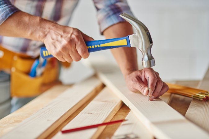 iStock-615419086 parts of a nail man hammering nail into construction project