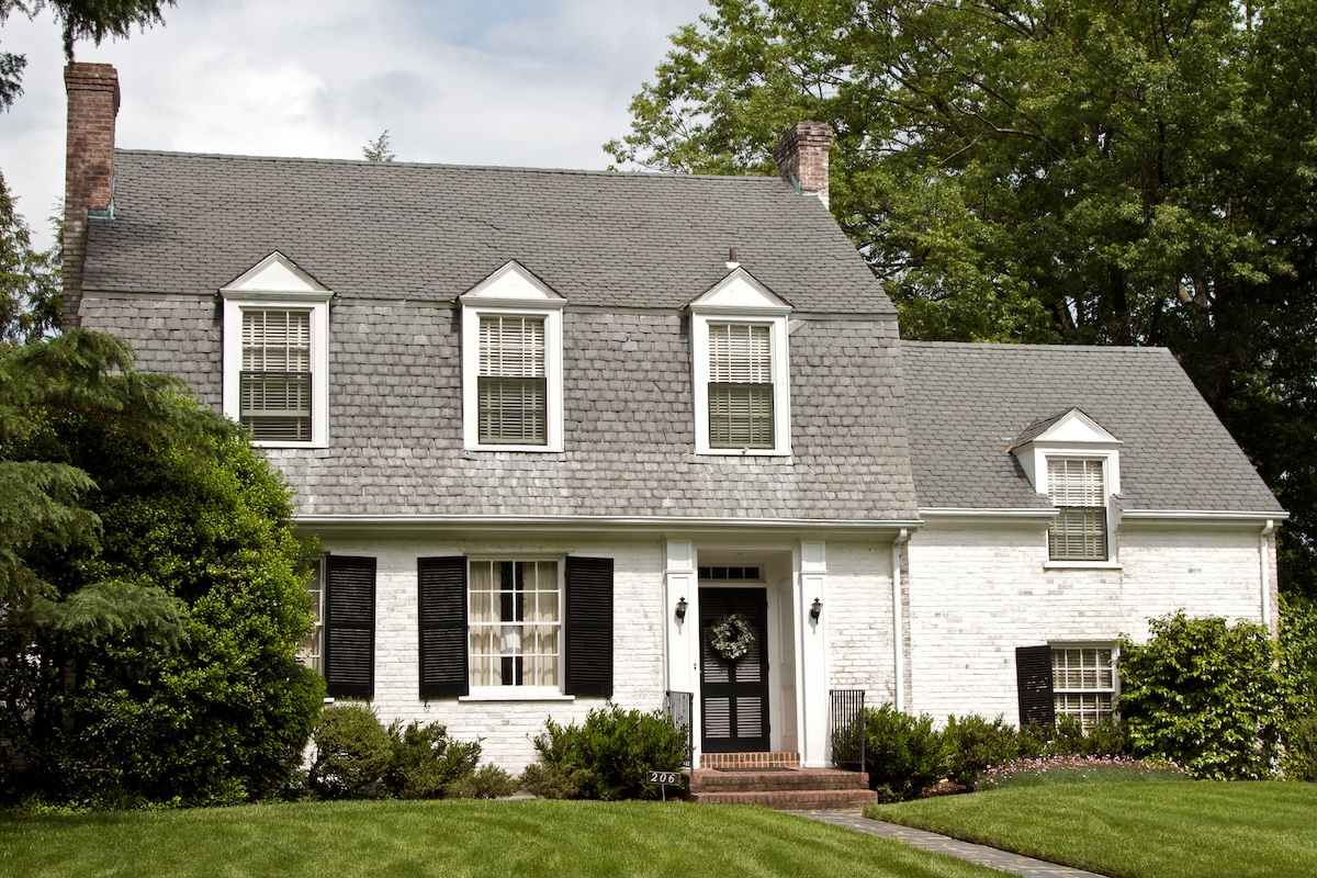 A farmhouse style home painted white with black trim and window treatments.