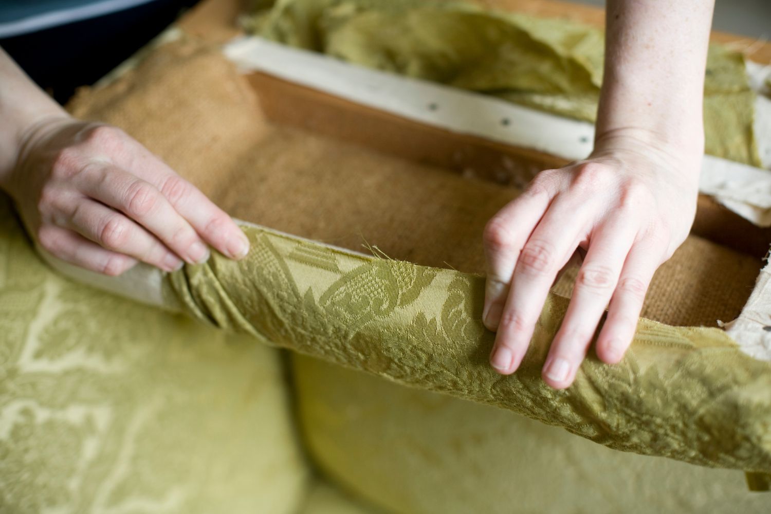 A chair being reupholstered with a light green fabric.