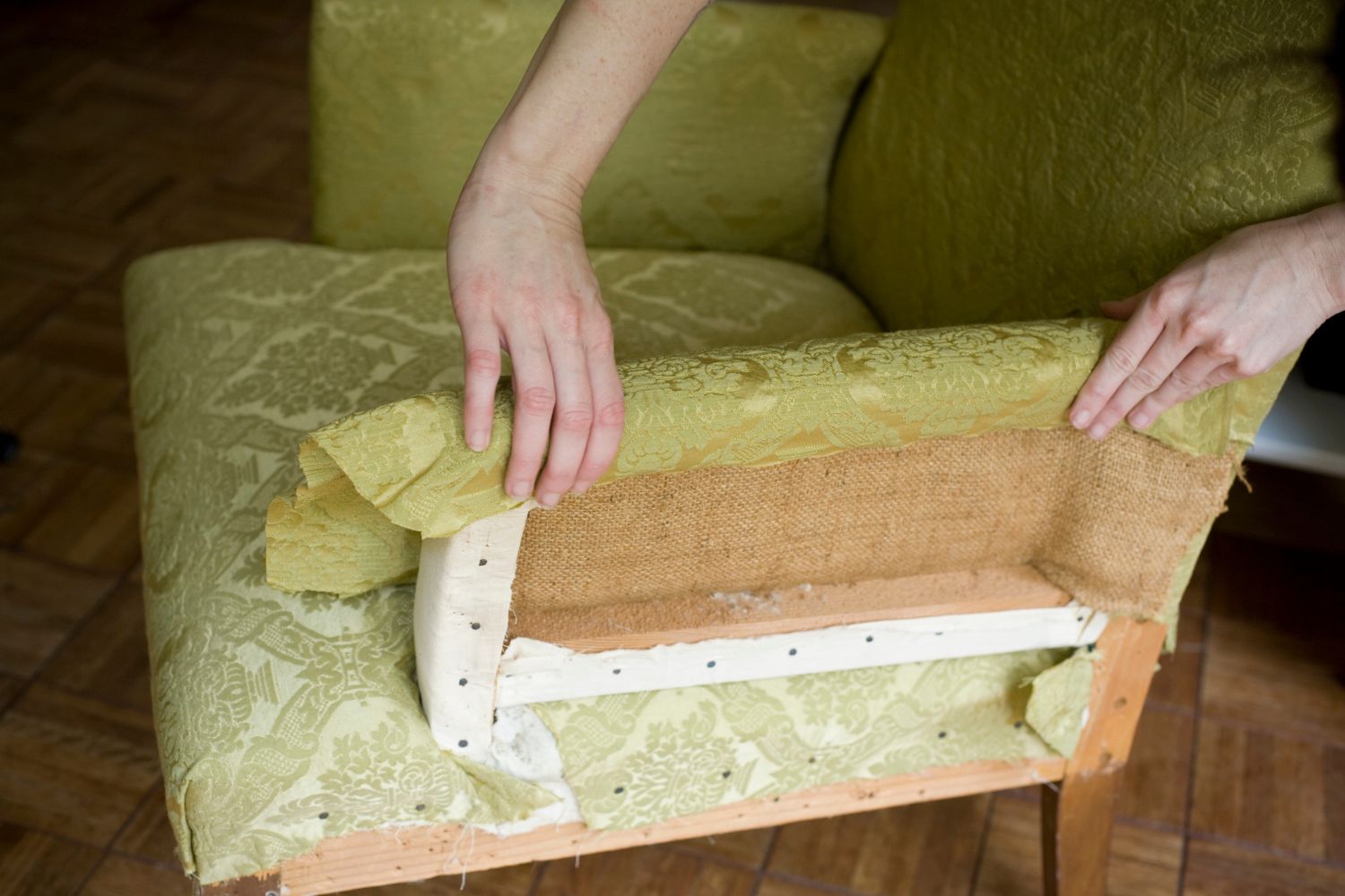 A chair being reupholstered with a light green fabric.