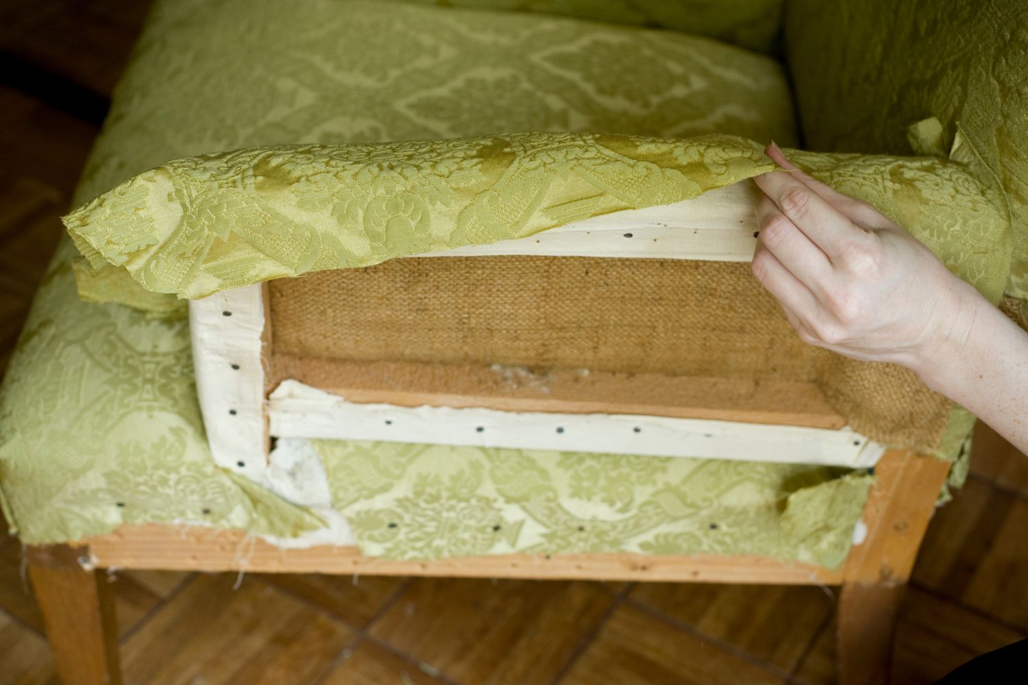 A chair being reupholstered with a light green fabric.