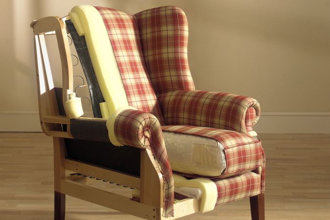 An old armchair with red and beige plaid material in the process of being reupholstered.