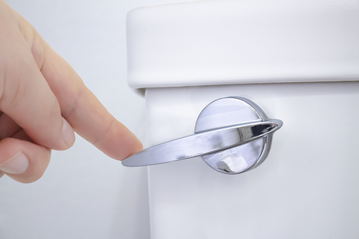 Closeup of hand flushing a toilet