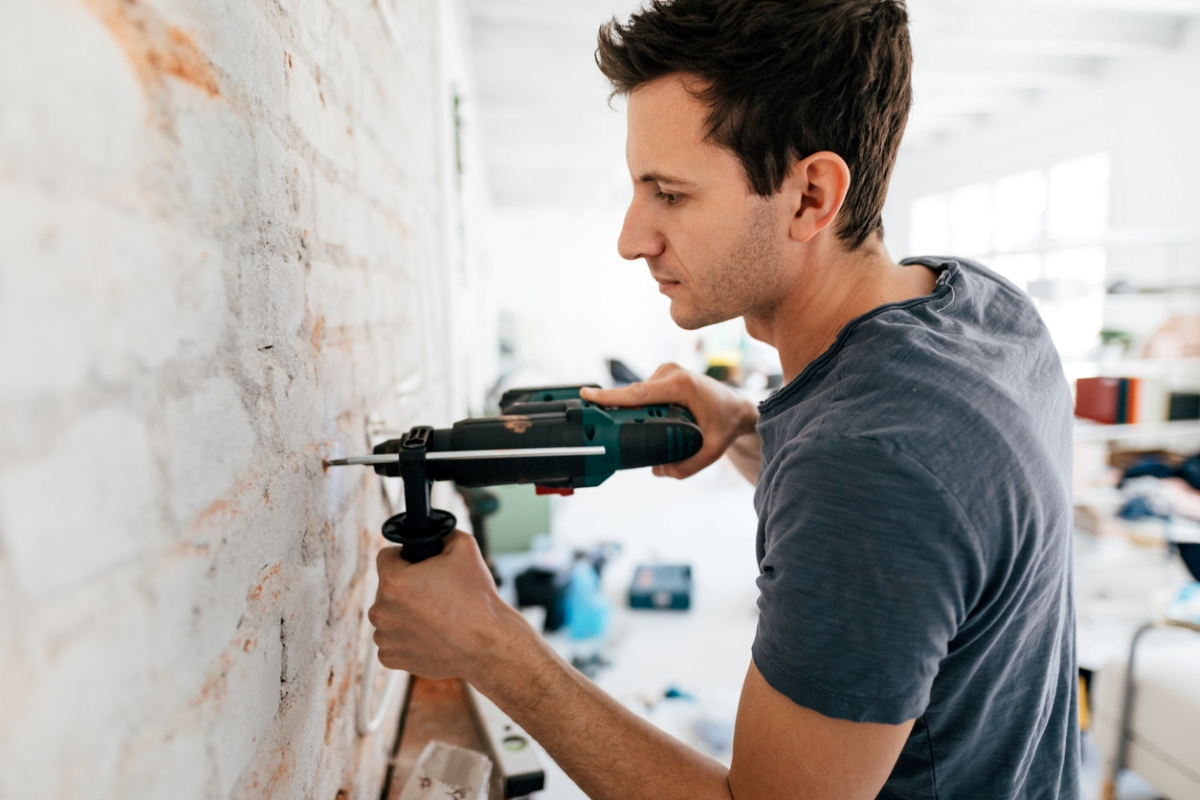 useful power drill attachments - man drilling into brick wall