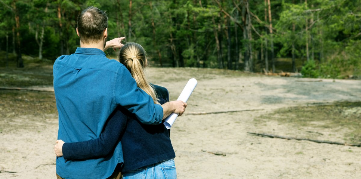 iStock-1312137939 cheapest places to buy land couple looking at land they bought to buy a home