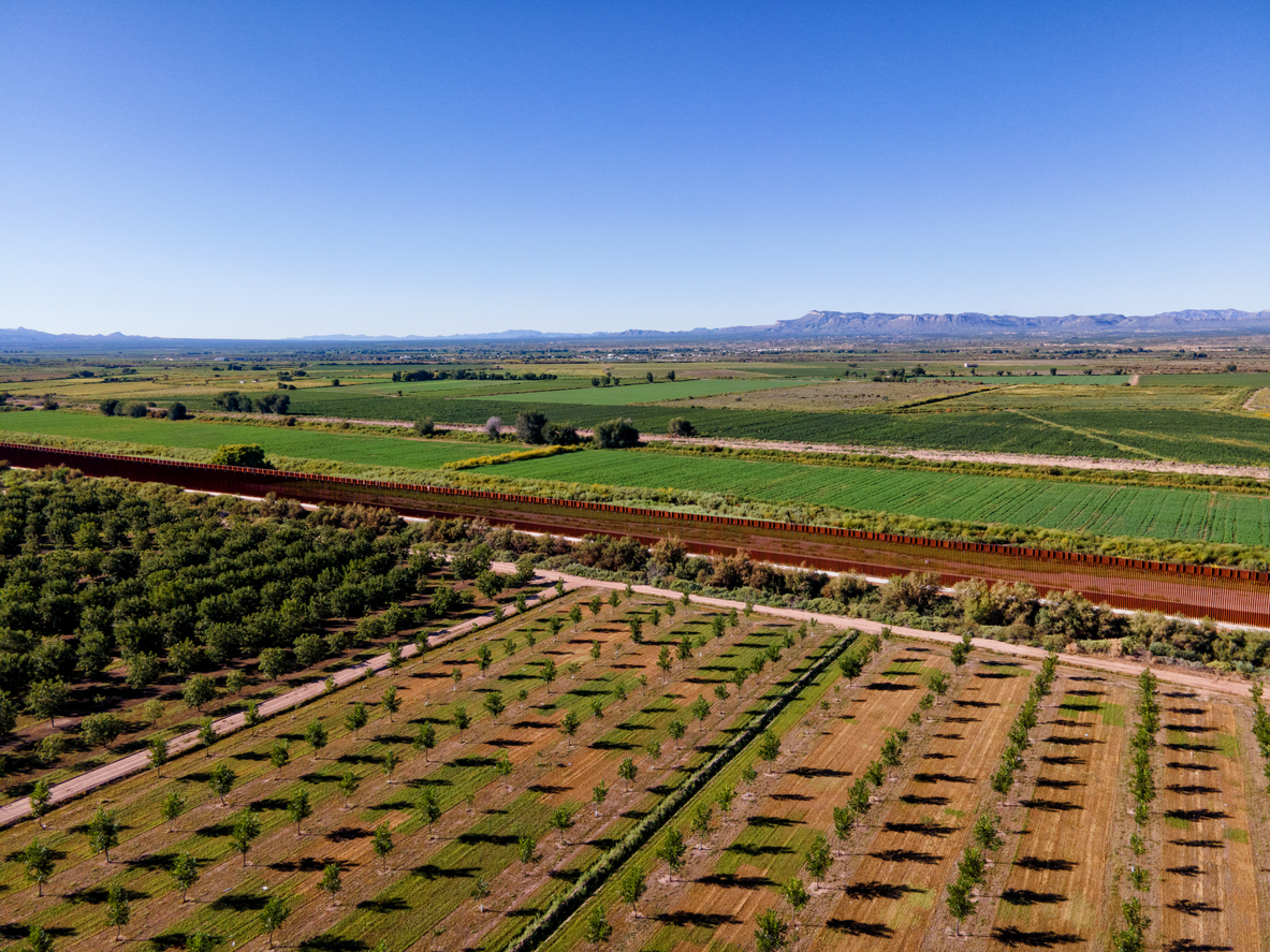 iStock-1465157796 cheapest places to buy land Border Wall Between Chihuahua Mexico and Texas at Fort Hancock with Orchard and Agricultural Fields on a Sunny Late Afternoon