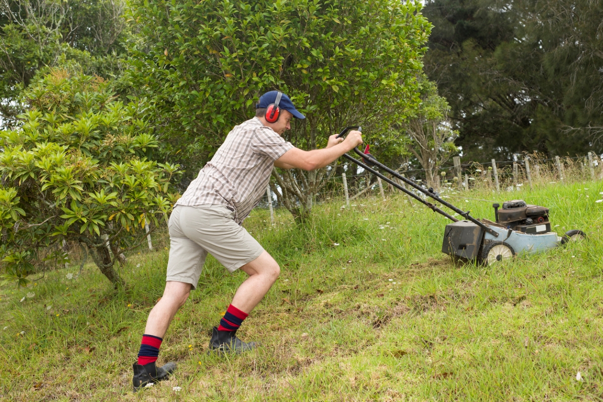 most dangerous power tools - man pushing lawnmower uphill