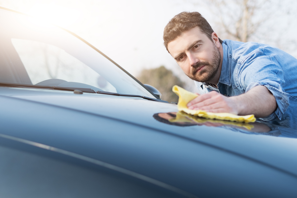 Man using cloth to clean the hood of his car