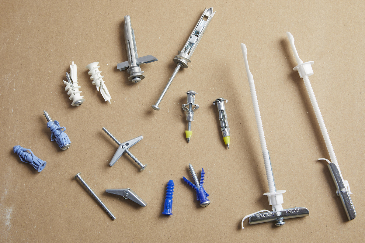 Many types of drywall anchors laid out against a brown background.