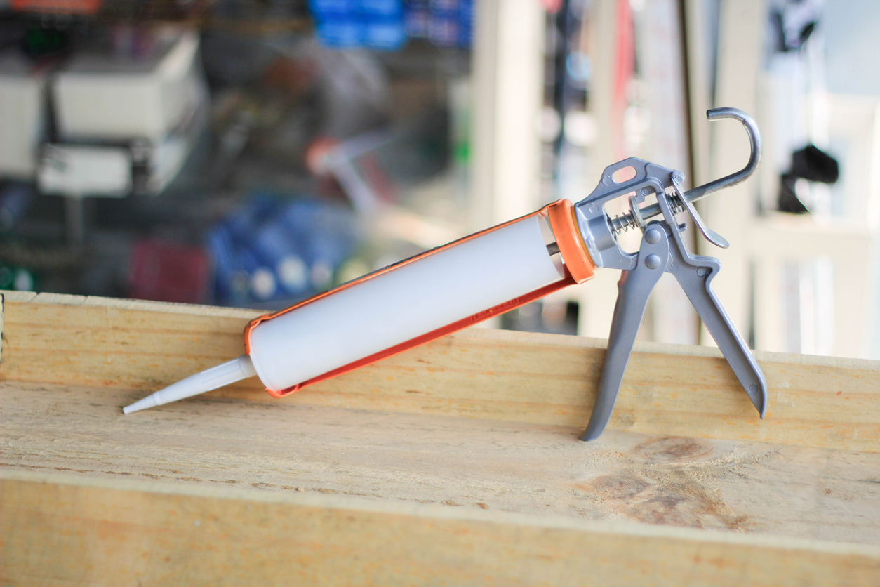 Caulking gun propped on an unfinished window frame.