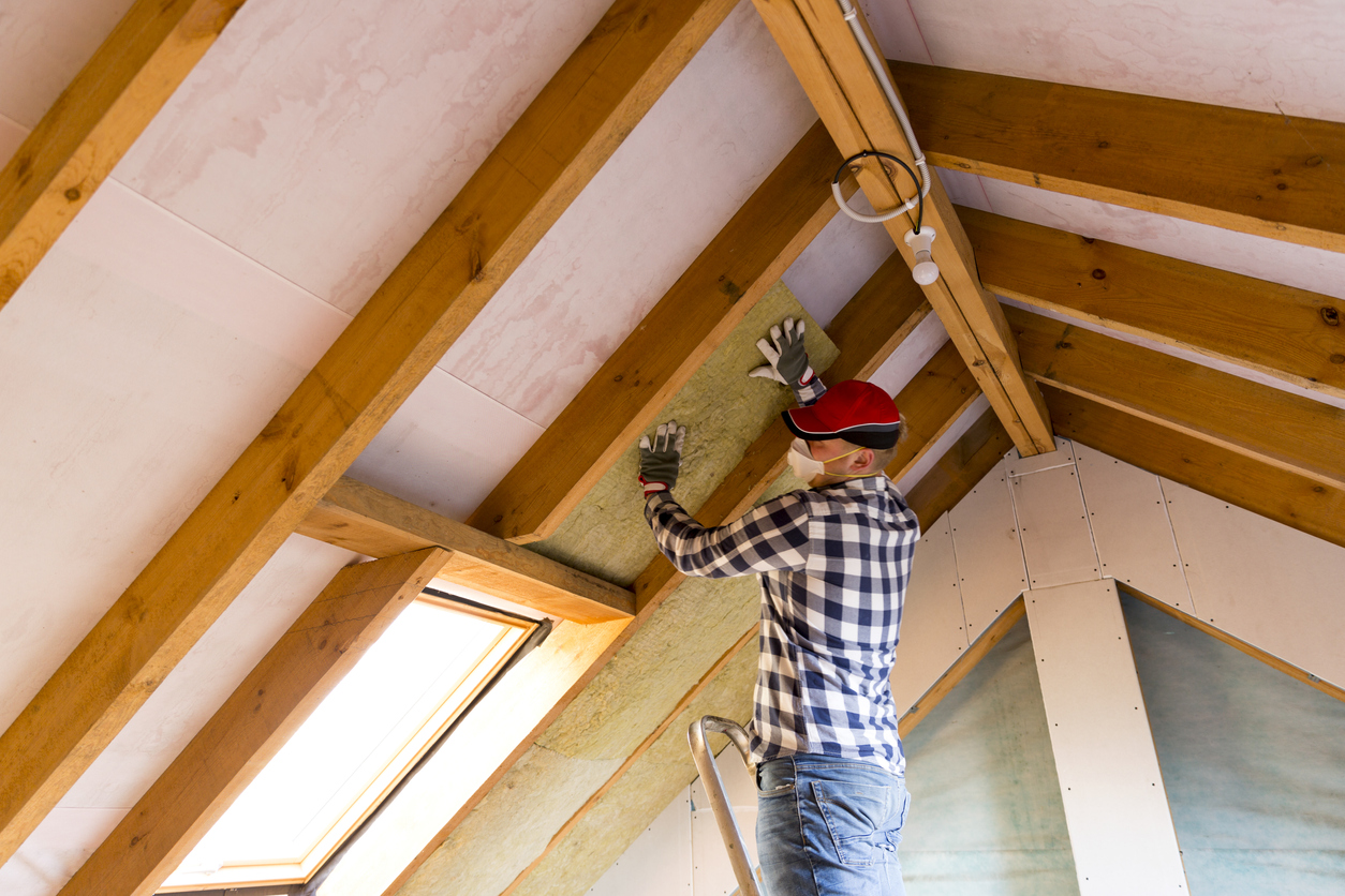 DIYer installing mineral wool panels in ceiling rafters