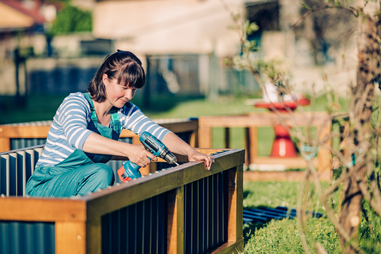 iStock-1318366155 14 Wise Ways to Weatherproof Your Garden Woman building raised planting bed