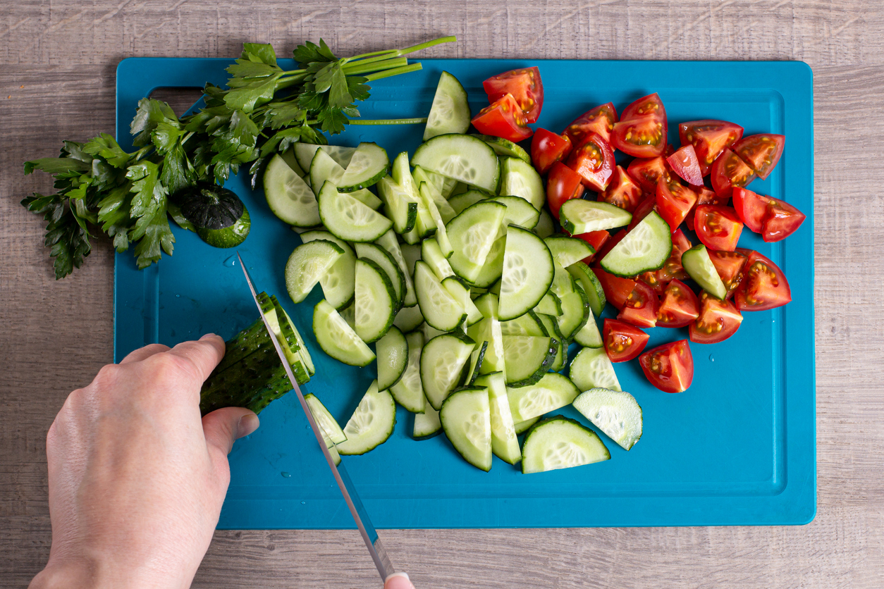 iStock-1322887287 save money gardening overhead of woman chopping cucumbers and tomatoes