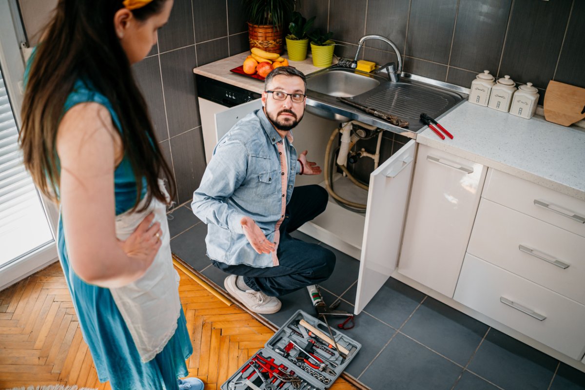 iStock-1324156899 how to unclog a drain man and woman looking at clogged drain