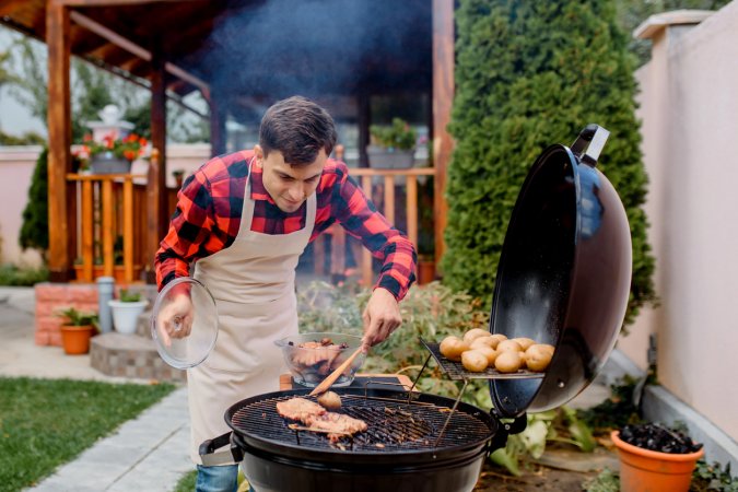 how to dispose of a grill man in apron cooking meat on round grill in backyard