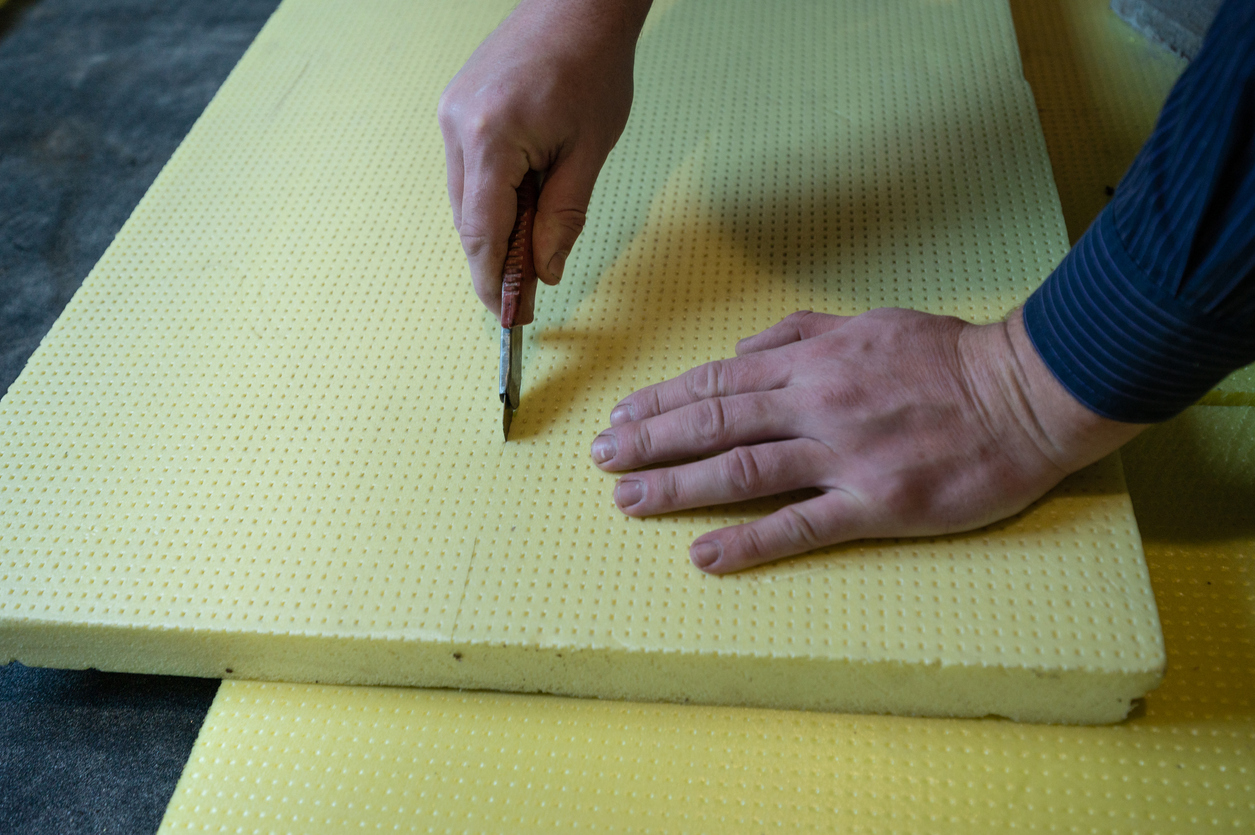 A man cuts expanded polystyrene on a floor.