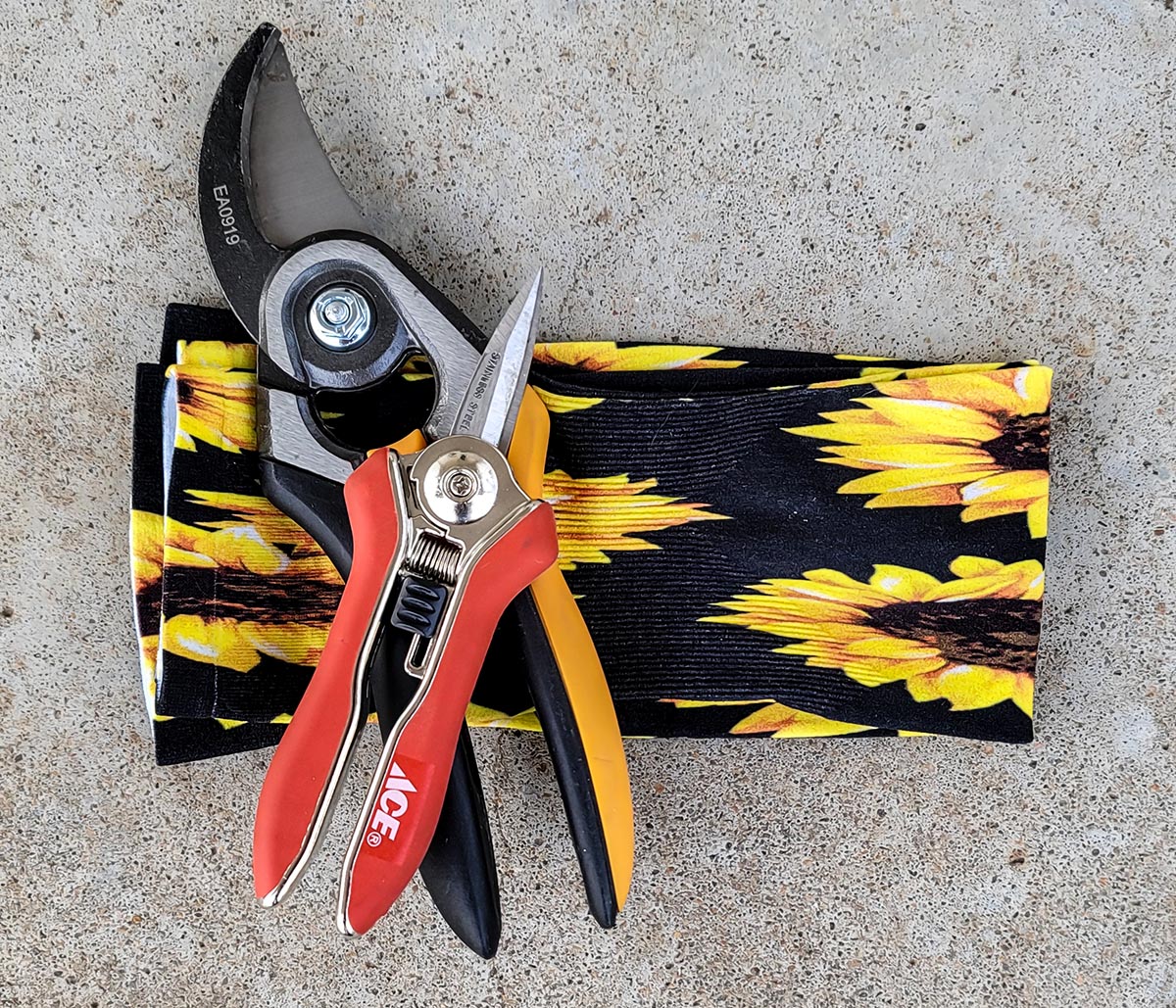 Wellday gardening sleeves lying on concrete alongside various gardening tools