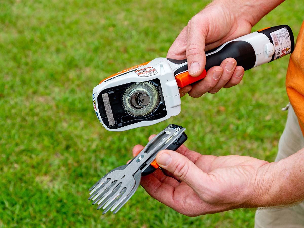 A man shows the quick-changing trimmer heads stored in the baseplate of the Stihl cordless garden shears