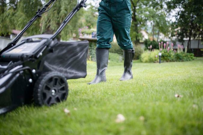 A close up of a person mowing a lawn.