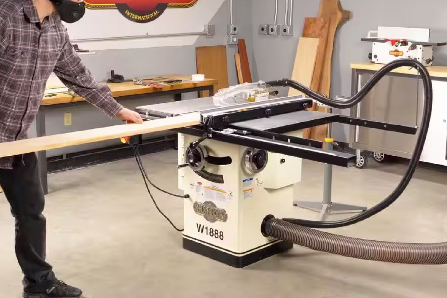 A man passing wood through a table saw in a workshop