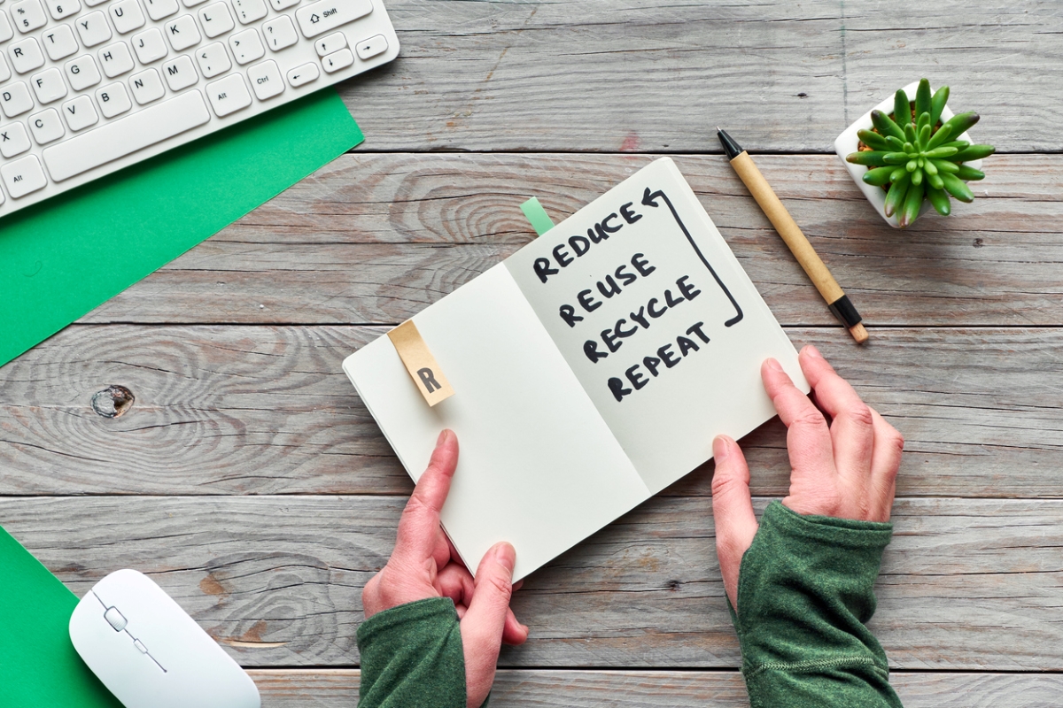 Person touching notebook with recycle notes written inside