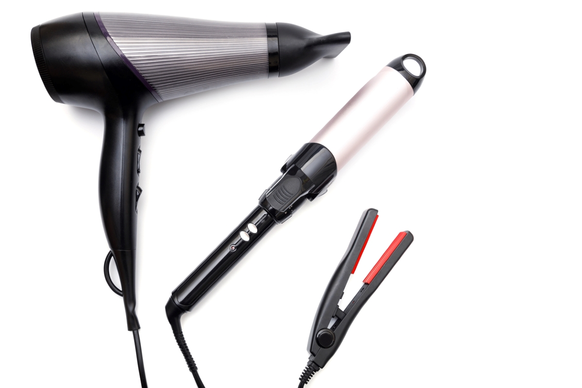 Hair styling tools including a hair dryer and curling iron on a white background.