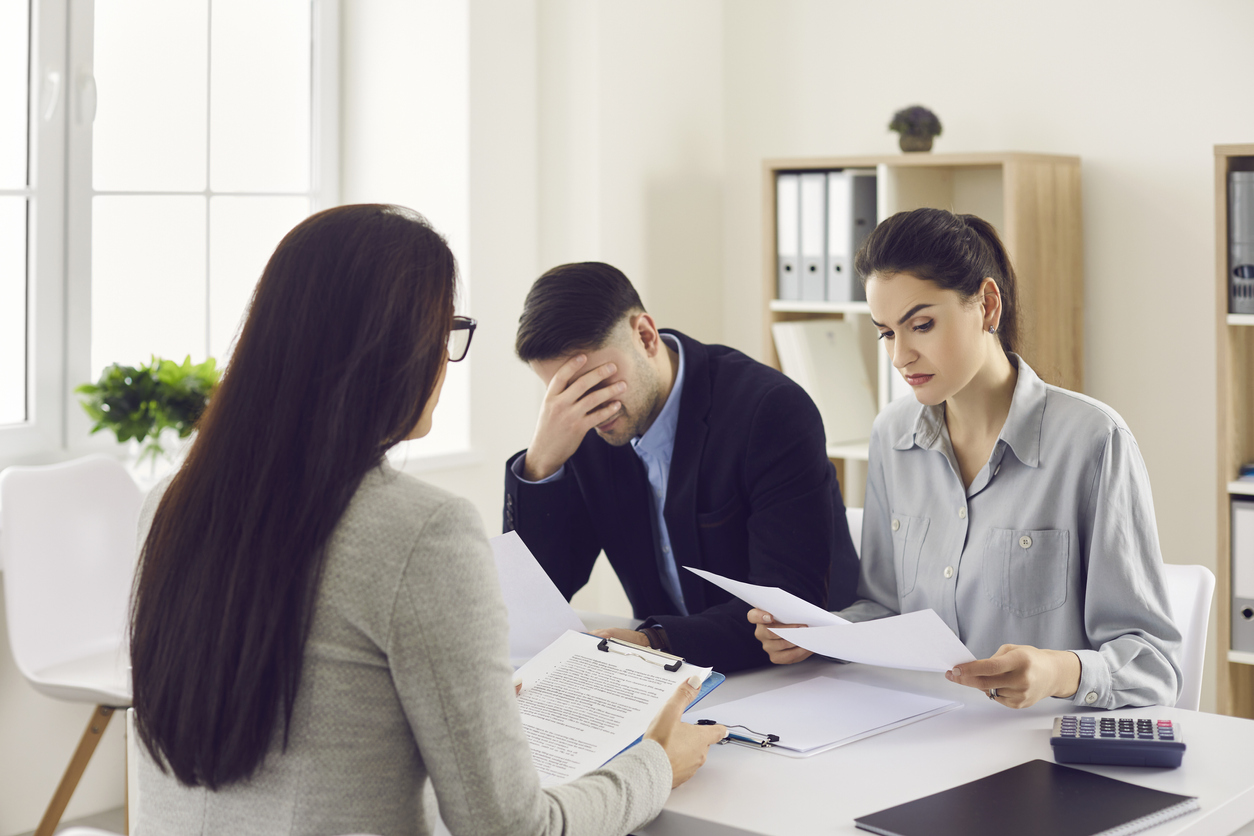 loan broker sitting at office desk and giving bad news to clients