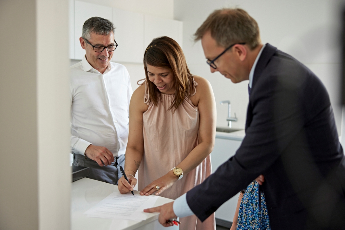 Older couple signing document with male agent