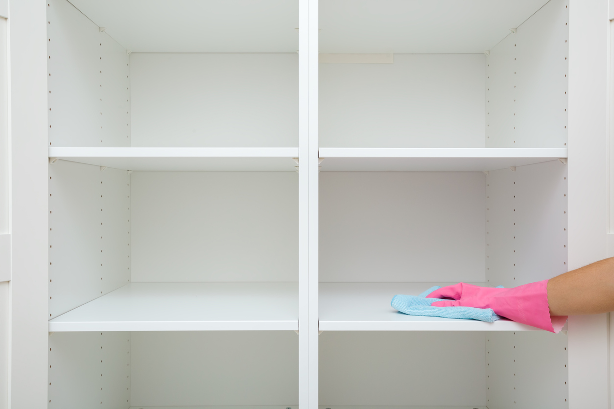 woman with pink rubber glove dusting shelves of closet