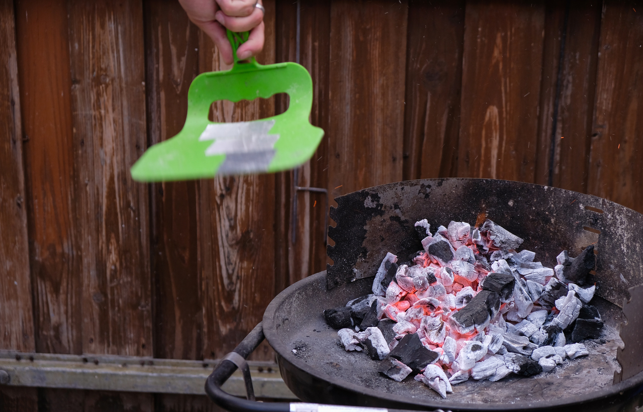 man's hand ready to pick up hot charcoal from the BBQ