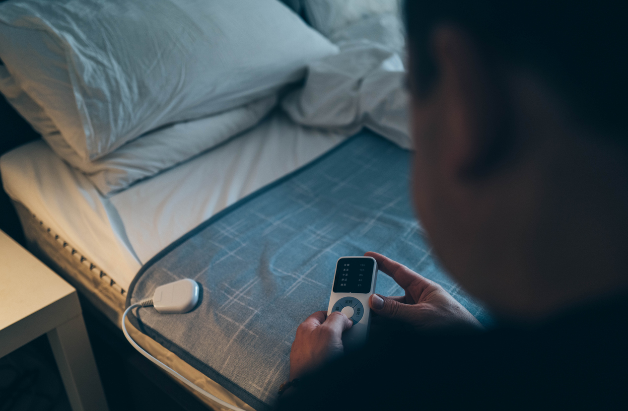 overhead shot of man testing temperature of electric blanket