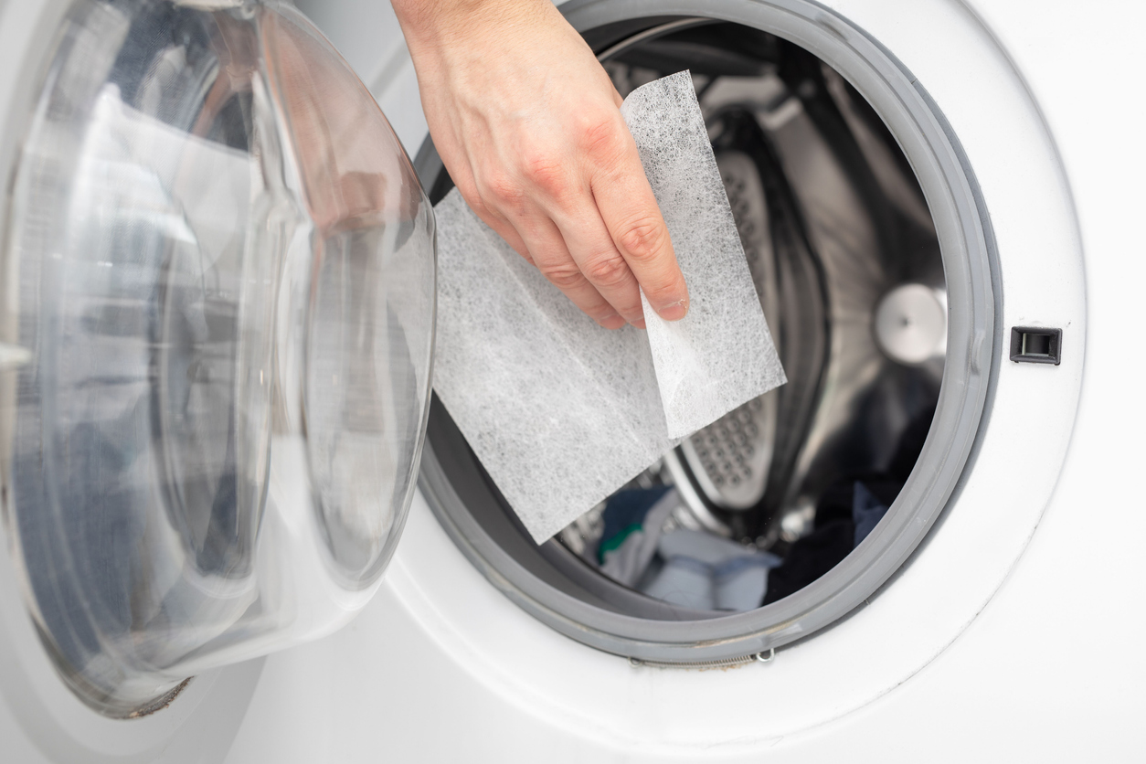 woman's hand placing a dryer sheet into the dryer